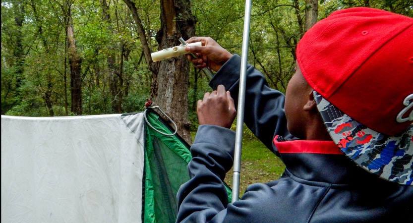 A person ties a knot for a tarp shelter. 